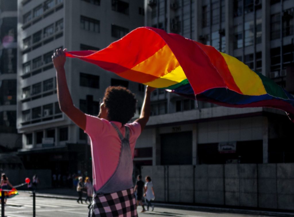 person walking with the rainbow flag flying over their head